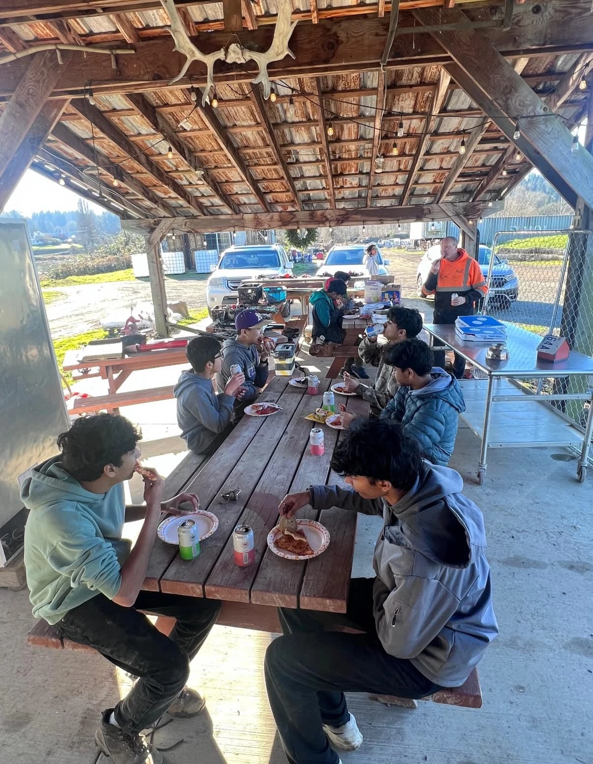 Volunteers eating pizza together at the farm after the greenhouse build
